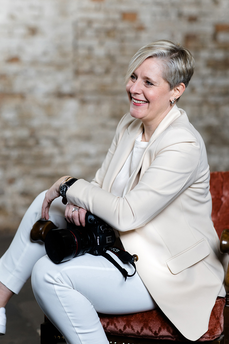 Storygraphin Jessica Krämer sitzend und lächelnd mit Kamera Portrait